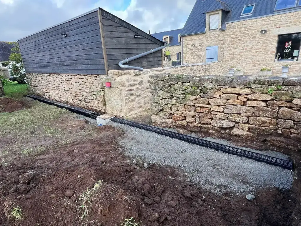 Caniveau de drainage des eaux pluviales le long d'un mur en pierre sèche, gestion des eaux en Finistère Sud