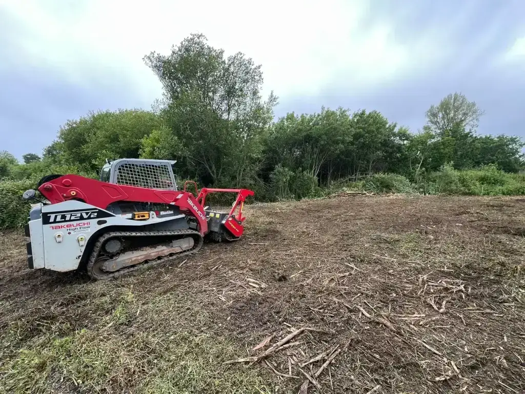 Chenillard Takeuchi TL12V2 de profil pendant le broyage de la parcelle à Fouesnant
