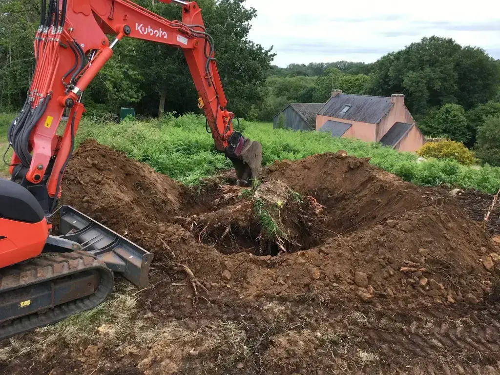 Arrachage d'une souche à la pelle mécanique Kubota en pleine campagne, dessouchage en Finistère Sud