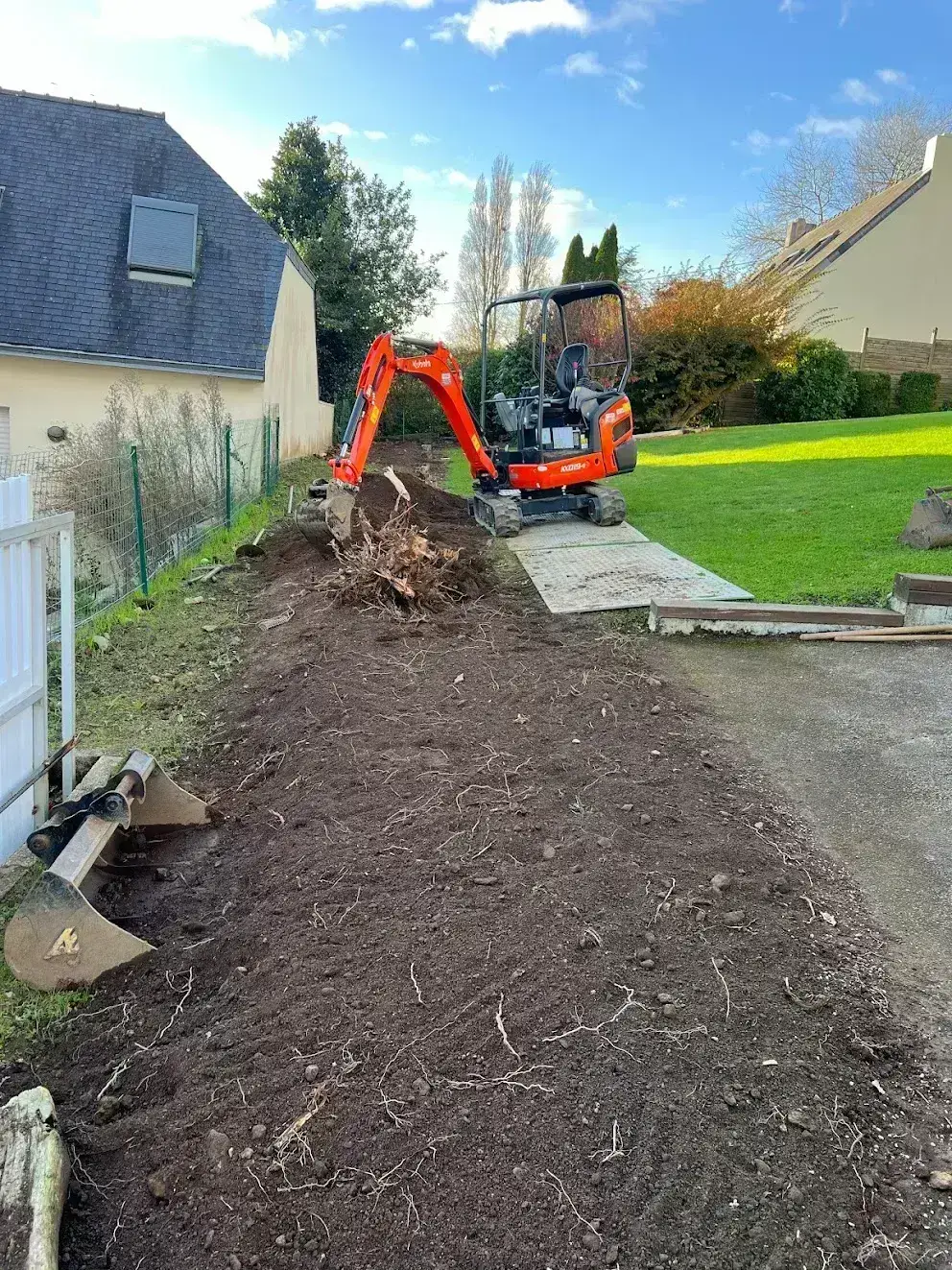 Souche extraite en bordure de jardin clôturé à la mini-pelle, dessouchage en Finistère Sud