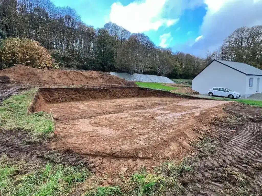 Décaissement de la plateforme de maison sur terrain en pente, terre ocre en lisière de sous-bois, terrassement en Finistère Sud